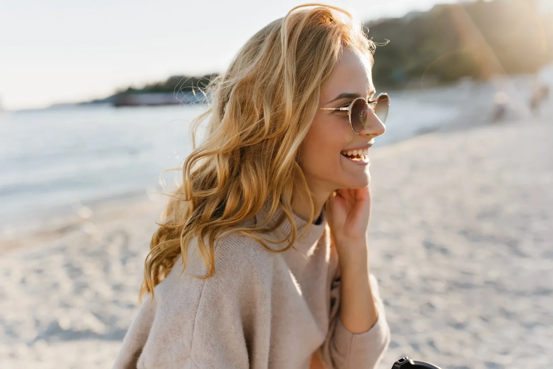 Smiling woman with sun-kissed blonde waves on a Lake Michigan beach near Muskegon