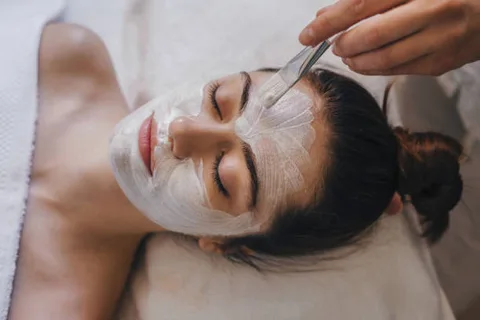 Client relaxing with a creamy facial mask being applied at Dockside Salon in Muskegon, MI