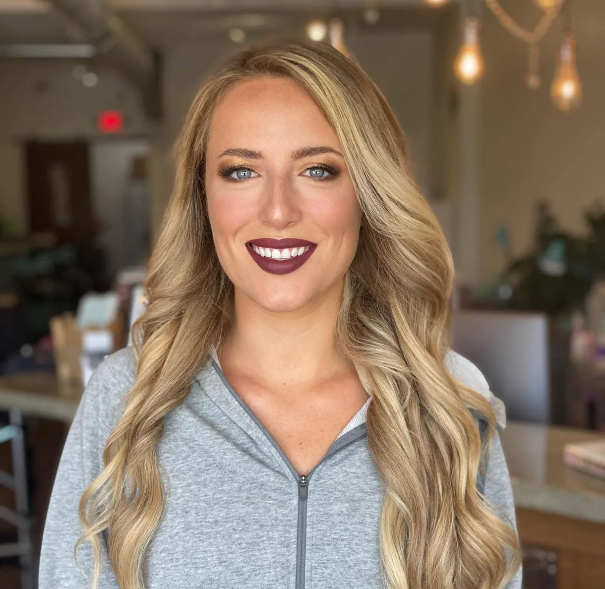 Smiling blonde client with bright white teeth and full glam at Dockside Salon in Muskegon, MI